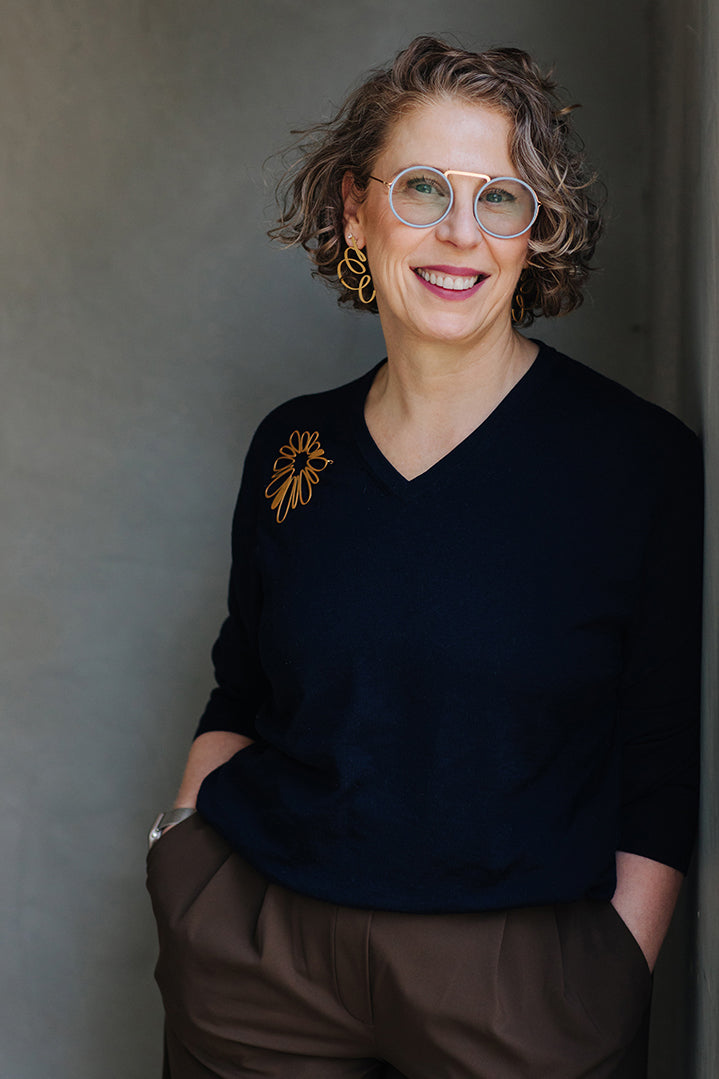 Iris Saar Isaacs wearing gold inSync earrings and a sculptural brooch