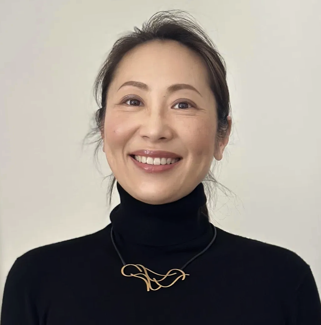 Woman wearing a gold sculptural necklace with black knitwear