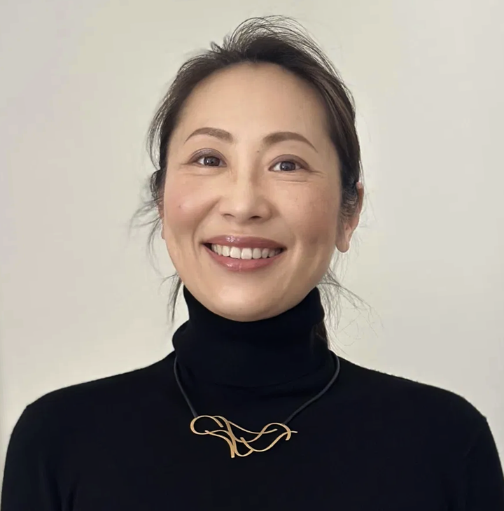 Woman wearing a gold sculptural necklace with black knitwear