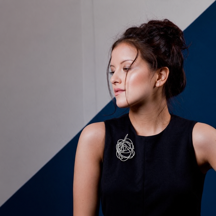 Model wearing the Scribble Brooch in raw stainless steel on a black dress